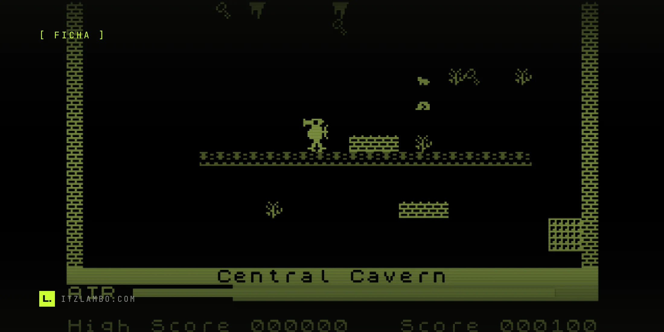Fotograma de Manic Miner (edición original de Bug-Byte, 1983) en Central Cavern: Miner Willy, con casco y overol rojo, está sobre una plataforma junto al guardián amarillo; arriba flotan llaves de colores y abajo se ven el medidor de aire y el marcador de puntos.